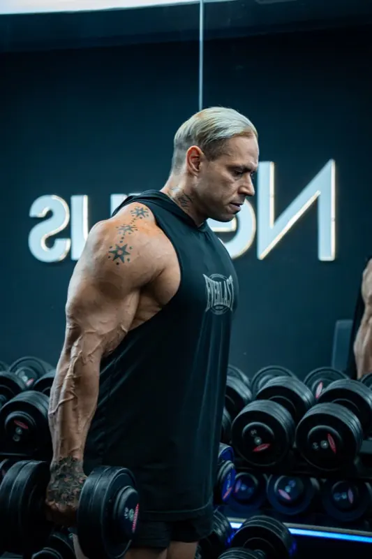 Ricardo de pie con una mancuerna en el gimnasio